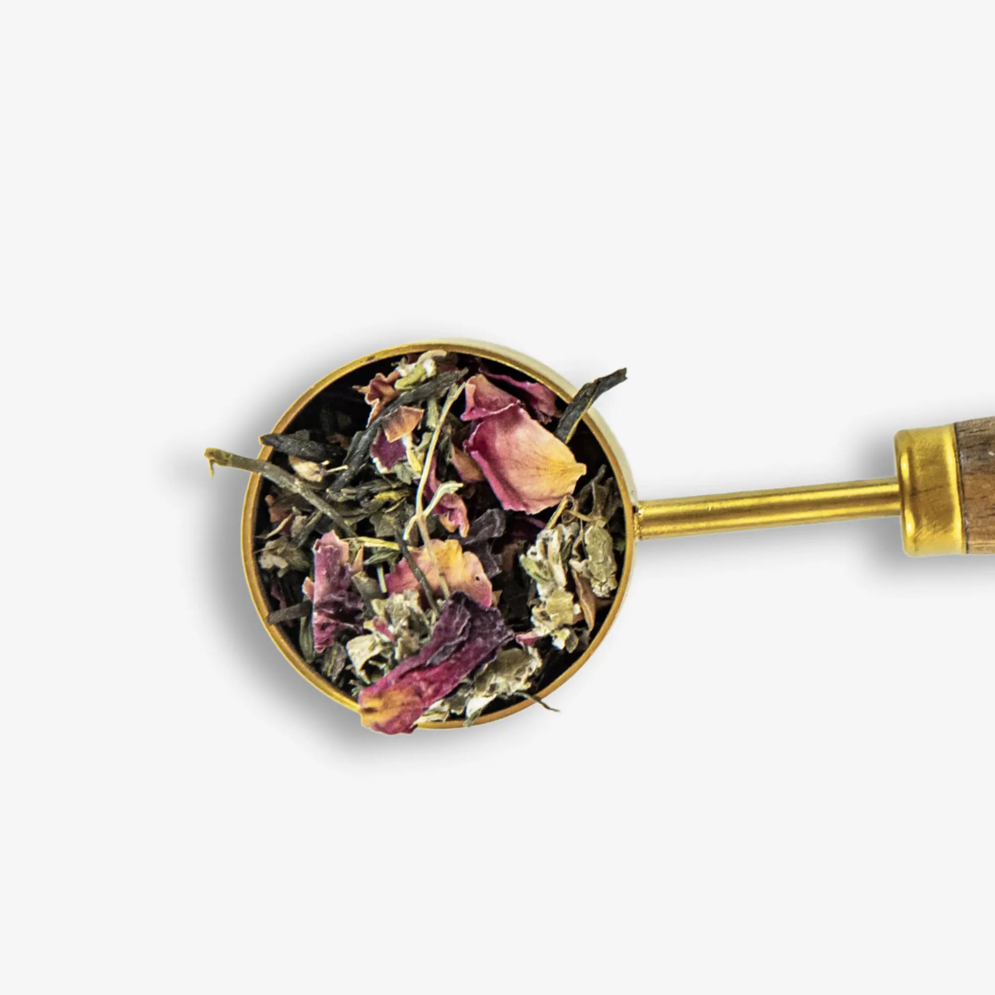 Close-up of PuriTea gold scoop filled with organic loose leaf tea, rose petals and botanicals