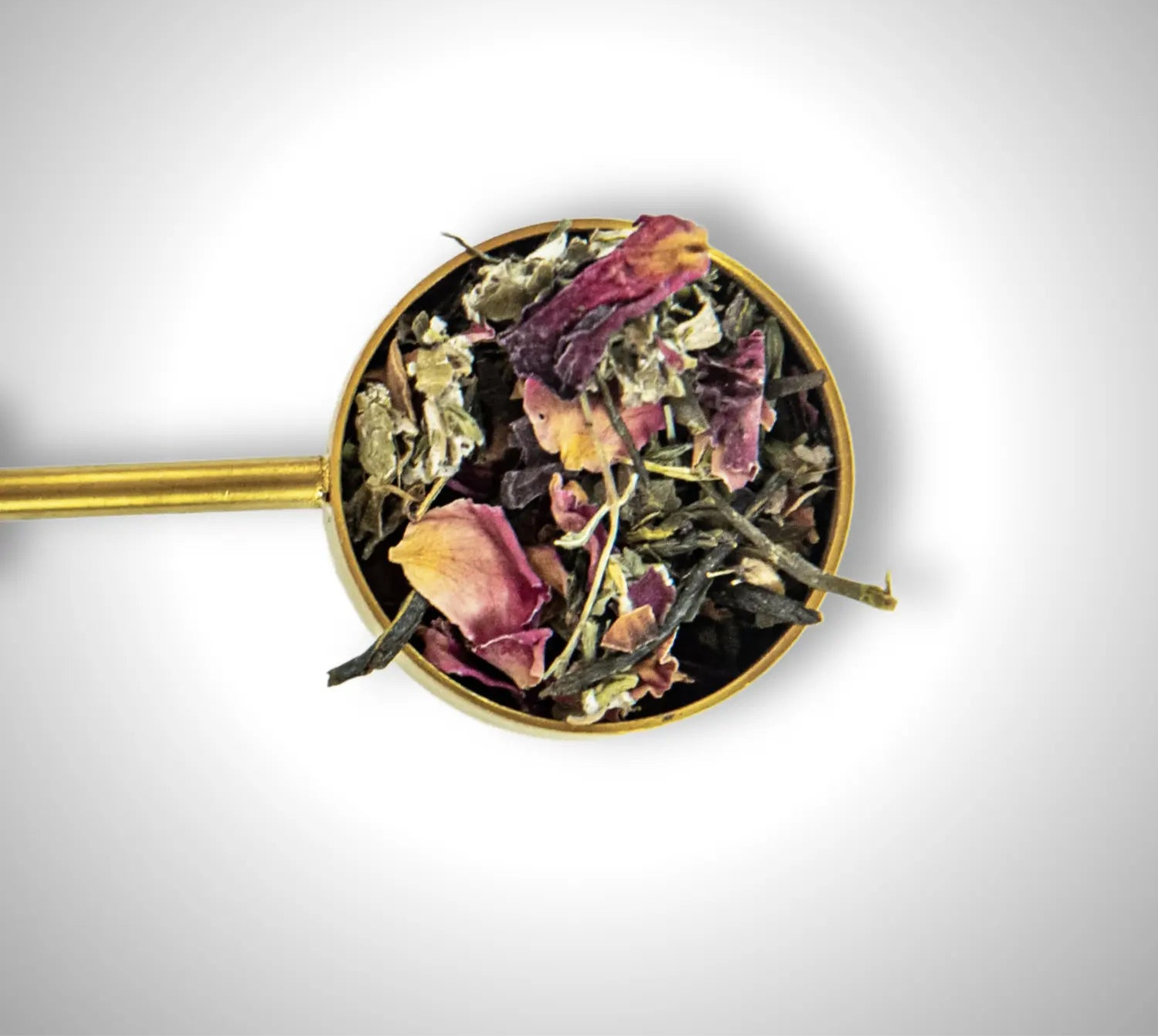 Organic loose leaf tea blend with healing botanicals, herbs and rose petals in gold scoop