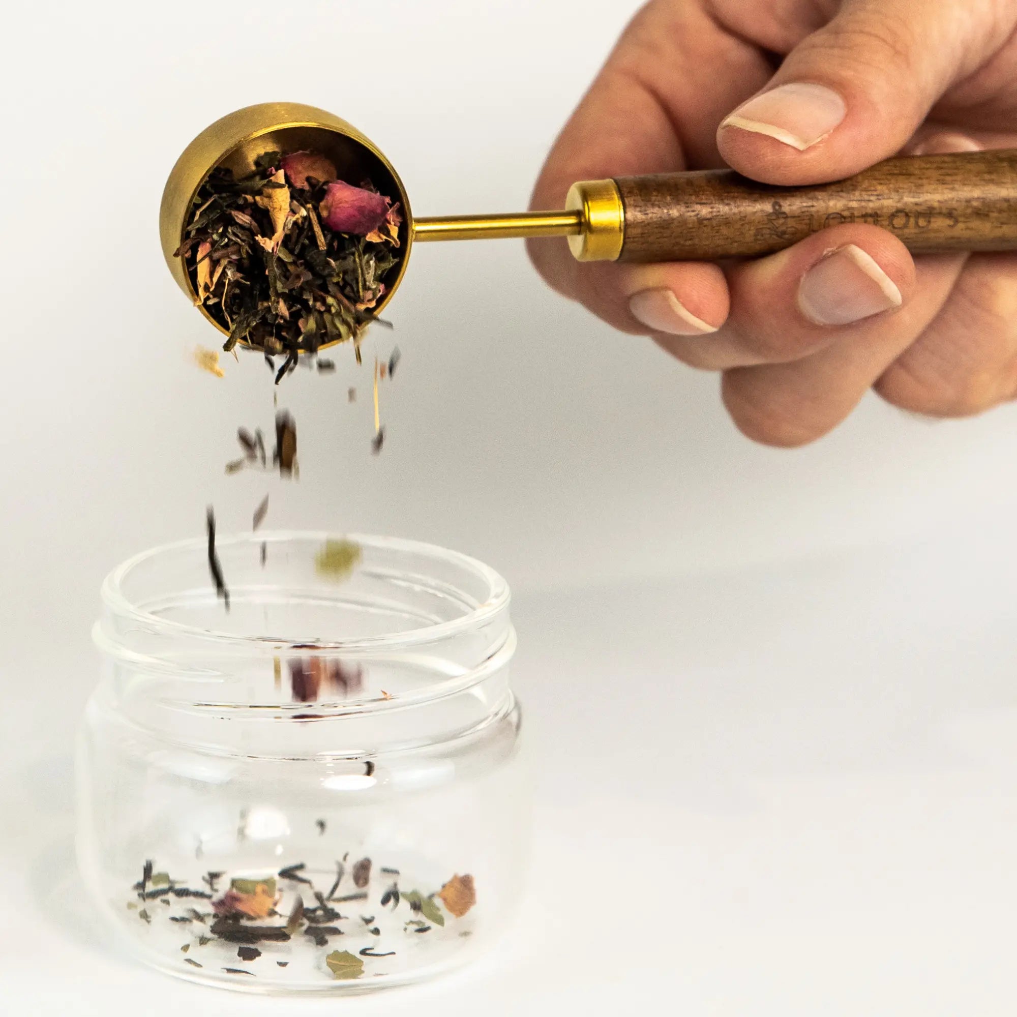 PuriTea scoop pouring organic loose leaf tea herbs and rose petals into glass infuser